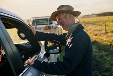 A farmer looking inside a car