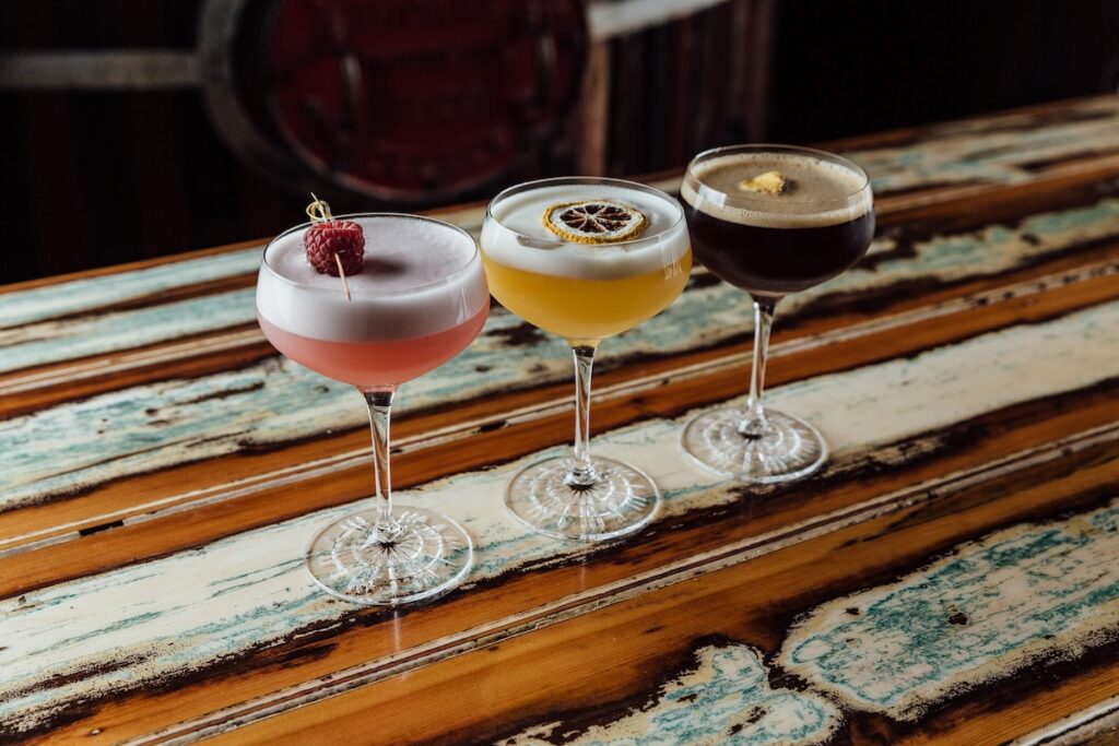 3 cocktails sitting on a wooden table