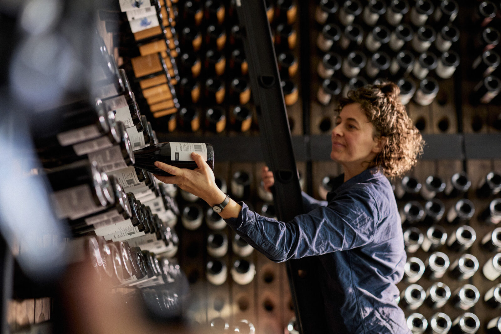 a person in a wine cellar retrieving a wine bottle