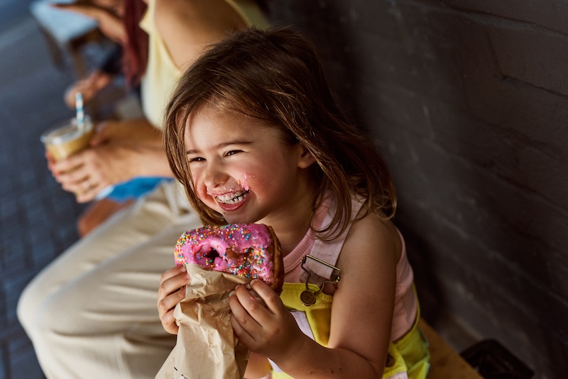 A young girl eating a donut with sprinkles