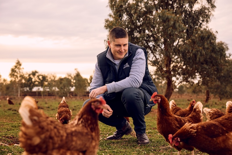 Martin Rhodes squatting down to look at Chickens on a farm