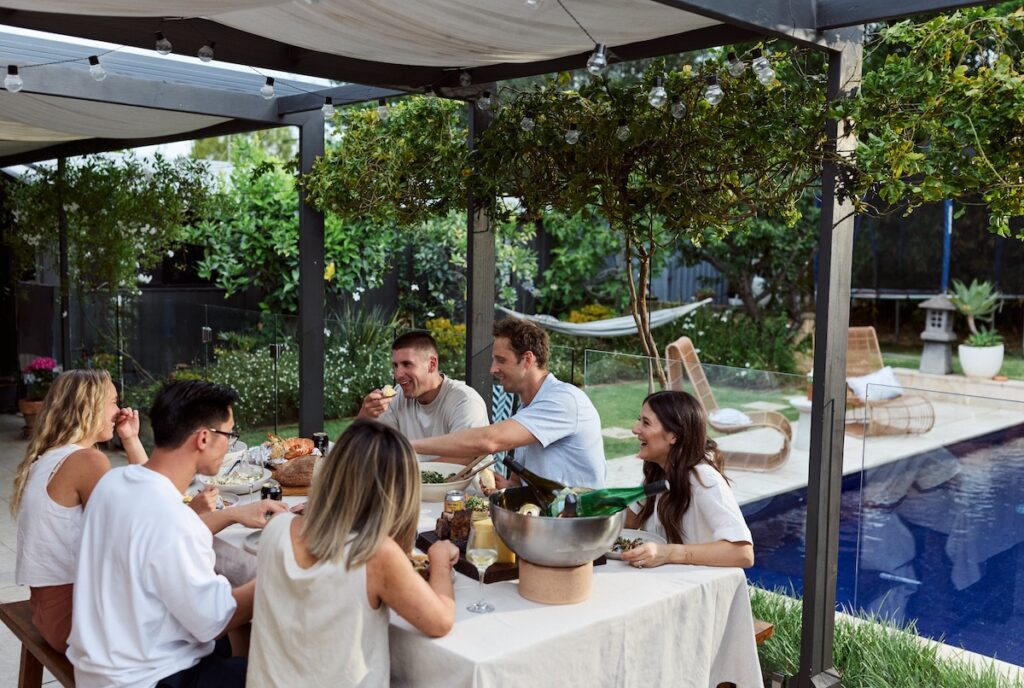 People dining in a backyard by a pool