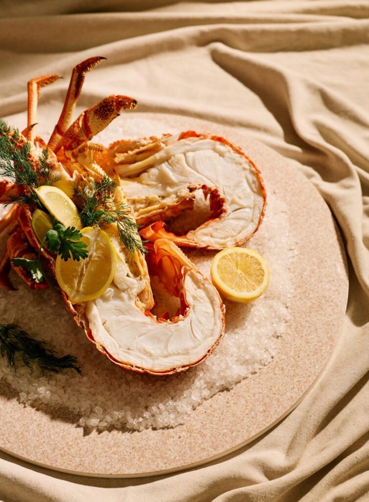South Australian lobster on a plate, decorated with a salt base and lemons, herbs