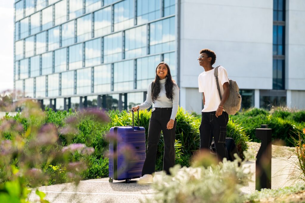 two students outside at Adelaide Airport with their luggage