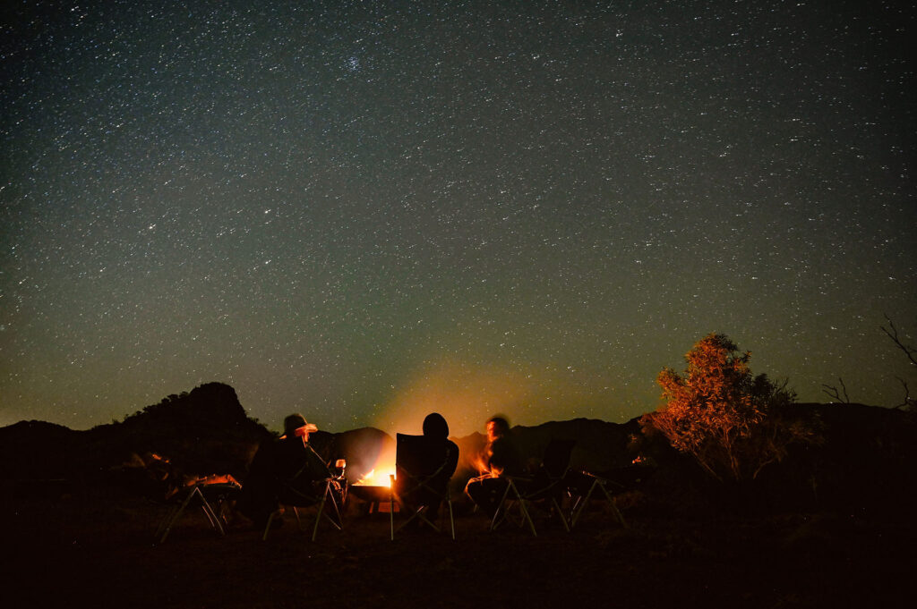 People sitting outside under the stars by a bonfire