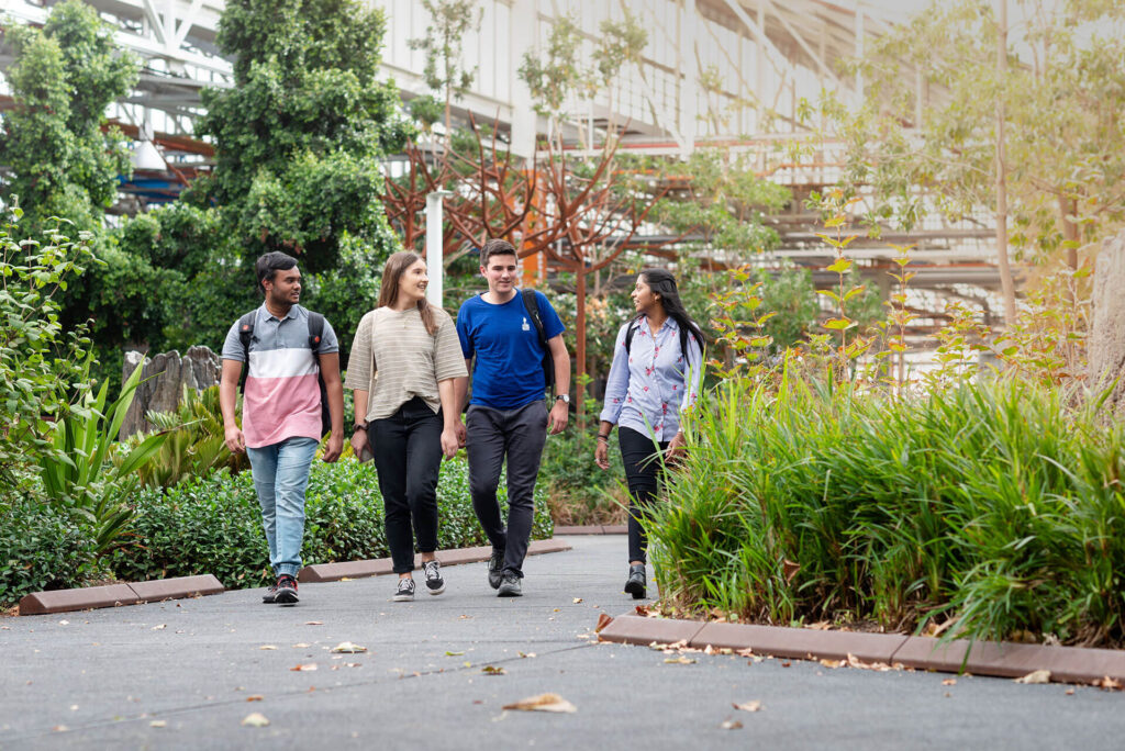 four students walking through the outside of the flinders university campus